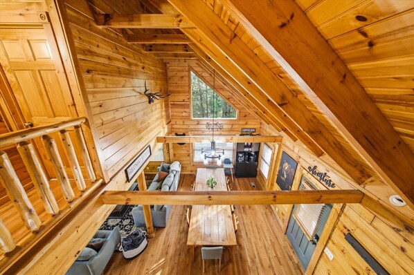 A wooden cabin interior with a dining area, a coffee bar, and a loft bedroom. - The Big Easy Renovated Near Attractions (Gatlinburg)