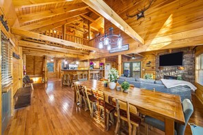 A wooden cabin interior with a dining area, kitchen, and living room. - The Big Easy Renovated Near Attractions (Gatlinburg)