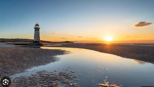 Majakka auringonlaskun aikaan, ja sen alla tyyni vesi, joka heijastaa taivasta.