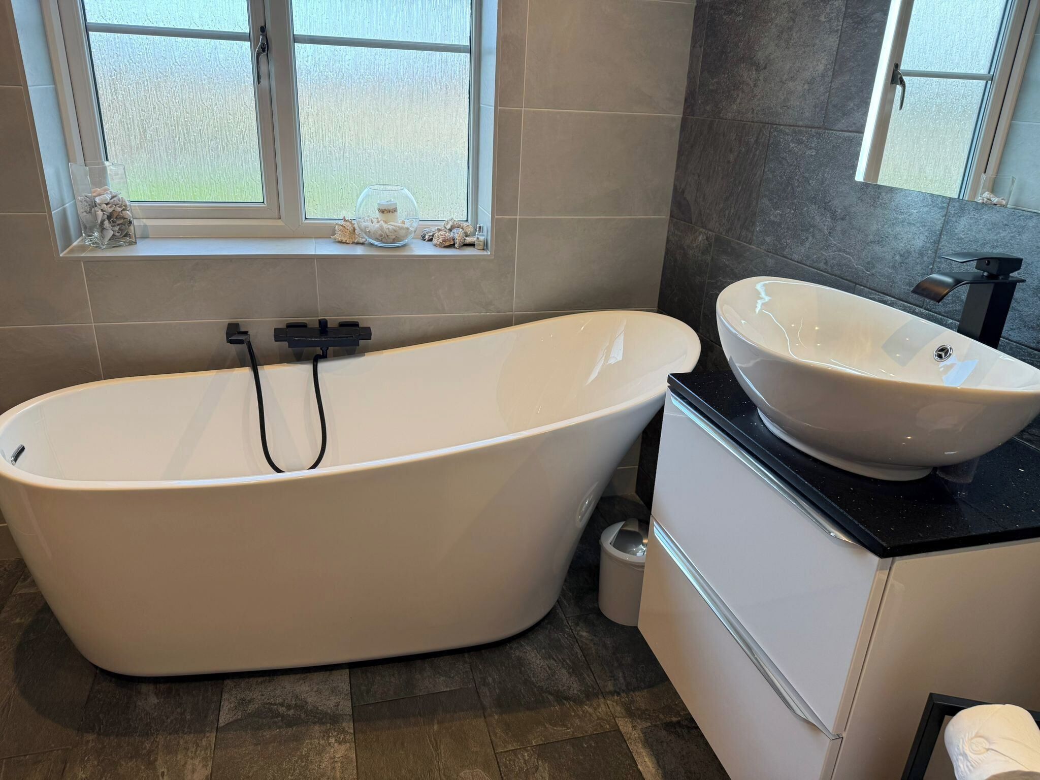 Un baño moderno con una bañera independiente, un lavabo sobre encimera y un inodoro.