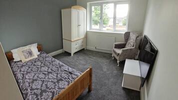 A bedroom with a bed, a wardrobe, a chair, and a radiator.