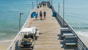 A wooden pier extending into the sea with benches and a lifeguard stand. - Sunsets on the Sound + Walk to the Beach (Atlantic Beach)