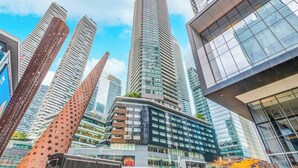 A modern urban skyline with high-rise buildings, including a distinctive curved structure and a building with a glass facade. - Lovely 1 BR Suite + Gym + Pool, MTCC, CN Tower (Toronto)