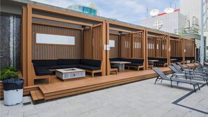 A modern outdoor seating area with wooden partitions, black cushioned seating, and a trash bin. - Lovely 1 BR Suite + Gym + Pool, MTCC, CN Tower (Toronto)