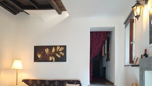A living room with a patterned sofa, a lamp, a wall art piece, and a staircase leading to another room. - Location Le 10&10 idromassaggio in camera Nepi VT (Nepi)