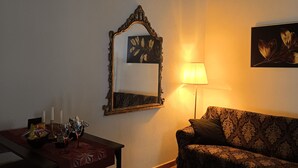 A cozy living room with a patterned sofa, a dining table with candles, and a wall-mounted mirror. - Location Le 10&10 idromassaggio in camera Nepi VT (Nepi)