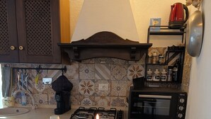 A kitchen with a gas stove, a microwave, and a coffee maker. There are candles on the counter, and a wine bottle and glasses are also visible. - Location Le 10&10 idromassaggio in camera Nepi VT (Nepi)