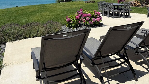Eine Terrasse mit Gartenmöbeln, einer Rasenfläche und Blick auf das Meer.