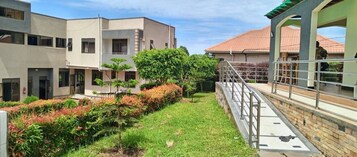Un patio con césped, un árbol y un edificio con tejado de baldosas.