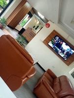 Un vestíbulo de hotel con asientos de cuero, una recepción y un televisor que muestra un programa.