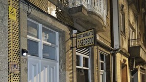 Eine Straße mit Gebäuden, darunter ein Restaurant namens „O Segredo“ mit einem Schild über dem Eingang.
