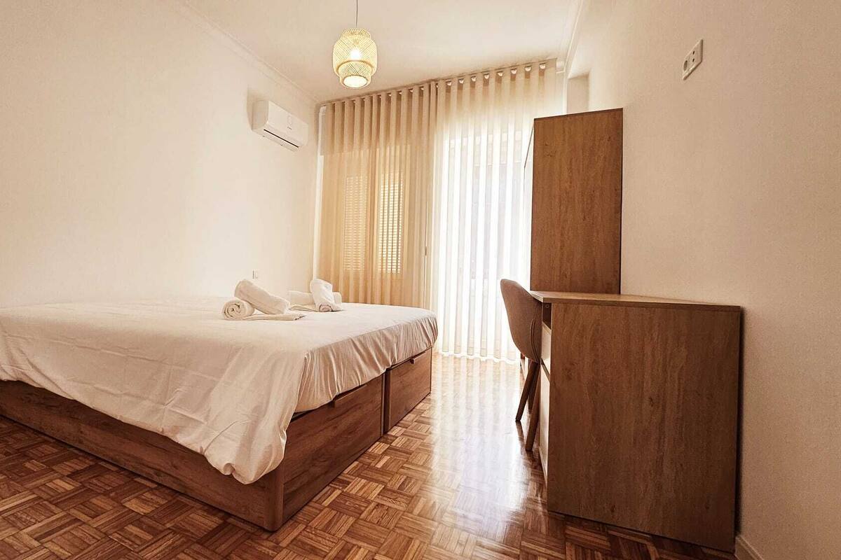 Une chambre avec un lit en bois, un bureau en bois et un luminaire suspendu.