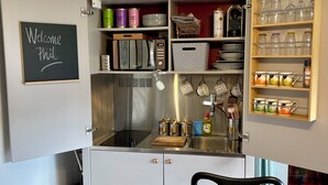 Une petite cuisine équipée, comprenant une cuisinière intégrée, un évier et un petit espace de rangement au-dessus du plan de travail.