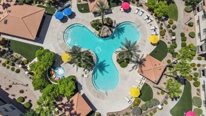 An aerial view of a resort with a central swimming pool, surrounded by palm trees, lounge chairs, and umbrellas. - ASU & Mill Ave | Sunny Getaway | Hot Tub & Gym (Tempe)