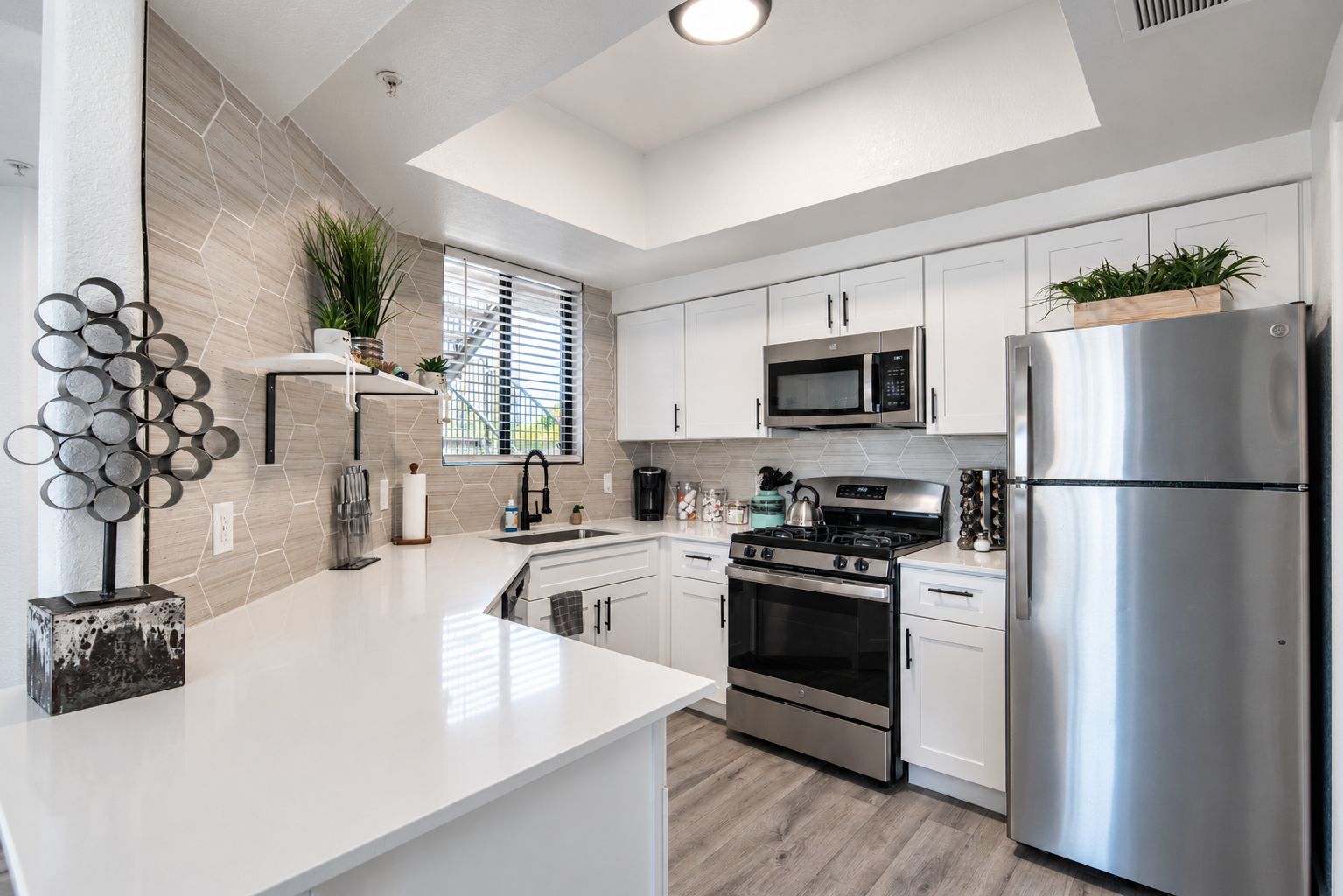 A modern kitchen with white cabinetry, stainless steel appliances, and a central island.
