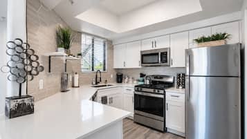 A modern kitchen with white cabinetry, stainless steel appliances, and a central island.