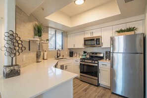 A modern kitchen with white cabinets, stainless steel appliances, and a central island.