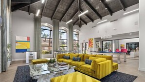 A spacious living area with a yellow sofa set, a glass coffee table, and a dining area with a pool table. - ASU & Mill Ave | Sunny Getaway | Hot Tub & Gym (Tempe)