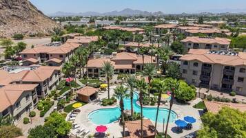 Un complejo turístico con varias edificaciones, una piscina central y palmeras.