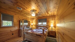 A wooden cabin bedroom with a bed, dresser, and two bedside tables.