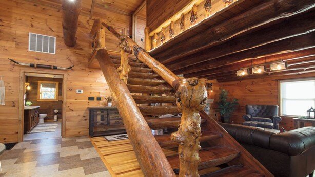 A wooden interior with a spiral staircase, a fireplace, and a leather sofa.