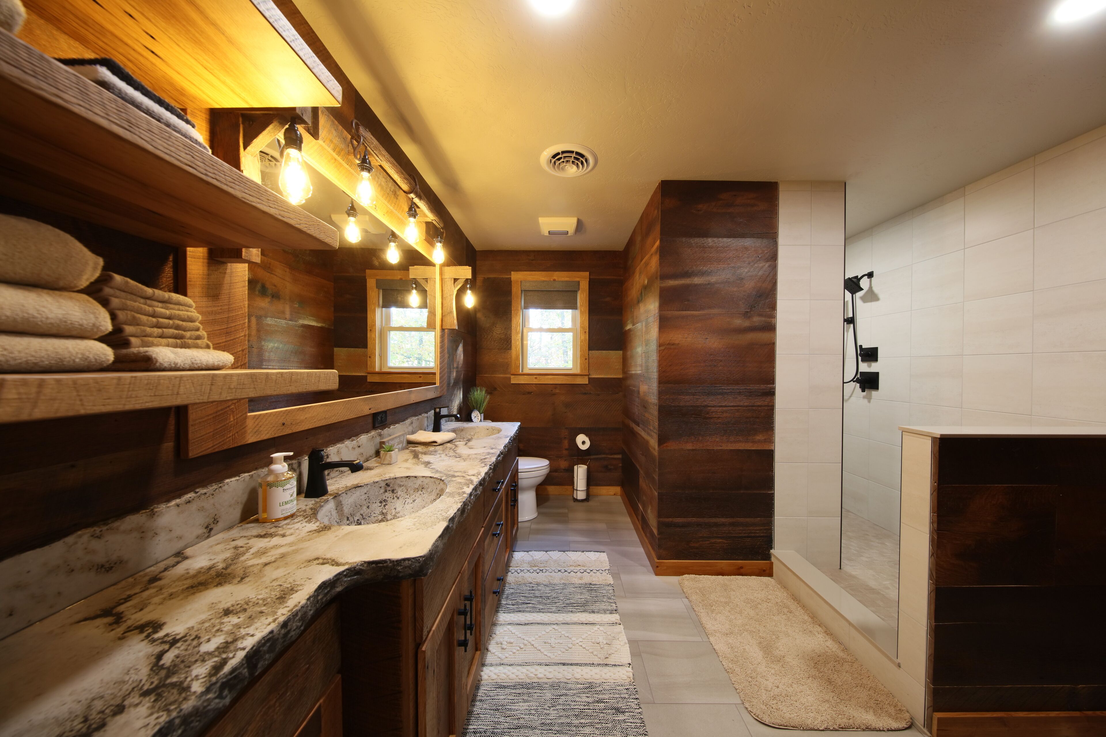 A modern bathroom with a wooden vanity, a large sink, a toilet, and a shower area.
