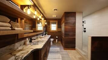 A modern bathroom with a wooden vanity, a large sink, a toilet, and a shower area.