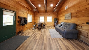 A log cabin interior with a dining area, a sofa, and a fireplace.