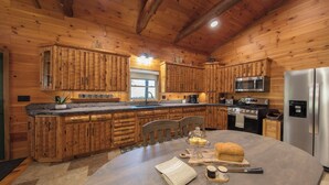 A wooden cabin interior with a kitchen featuring wooden cabinets, a stainless steel refrigerator, and a dining area with a table set for two.