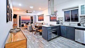 Cocina moderna con una isla integrada, muebles oscuros y vistas al atardecer a través del ventanal.