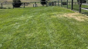 Un campo cubierto de hierba, con una valla y una cadena montañosa al fondo.