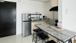 A modern kitchen with a marble countertop, black bar stools, a stainless steel refrigerator, and wooden cabinets. - WV Towers Studio with Balcony and Pool (Iloilo City)