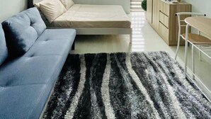 Una habitación pequeña con cama, sofá, escritorio y televisor.