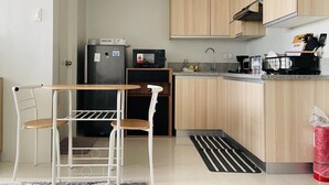 Cocina compacta con refrigerador, microondas, pileta y armarios de madera.