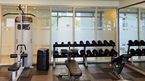 Une salle de sport équipée de machines d’exercice, d’un banc et d’un porte-haltères.