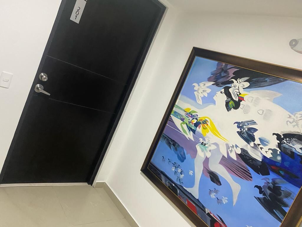 A hallway with a black door and a large abstract painting on the wall.