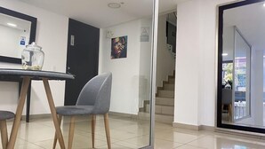 A modern interior with a dining area featuring a round table and two grey chairs. - Spacio30 (Bogotá)