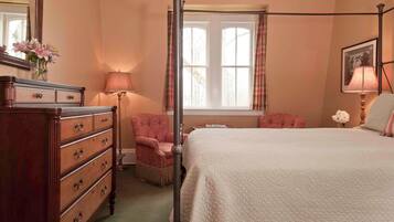 A bedroom with a four-poster bed, a dresser with multiple drawers, a chair, a window with curtains, and a lamp.