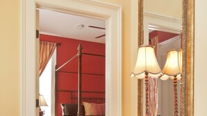 Un pasillo que conduce a un dormitorio con una cama, un aparador y un espejo grande.