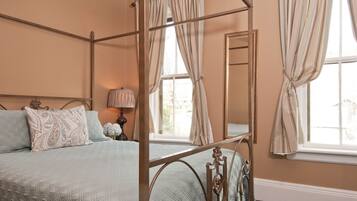 Un lit à baldaquin avec une couvre-lit matelassée, une table de chevet avec une lampe et un grand miroir au mur.