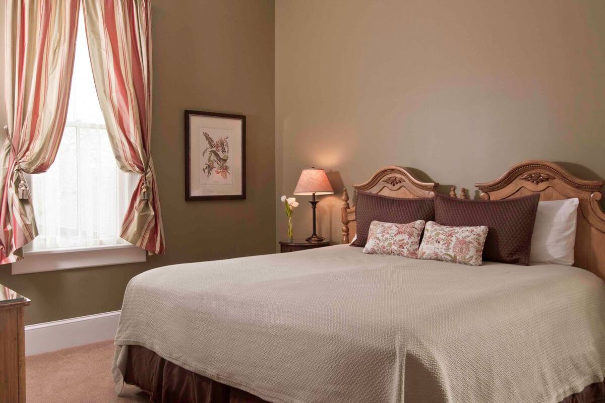 A neatly made bed with a wooden headboard, a bedside lamp, and a framed picture on the wall.