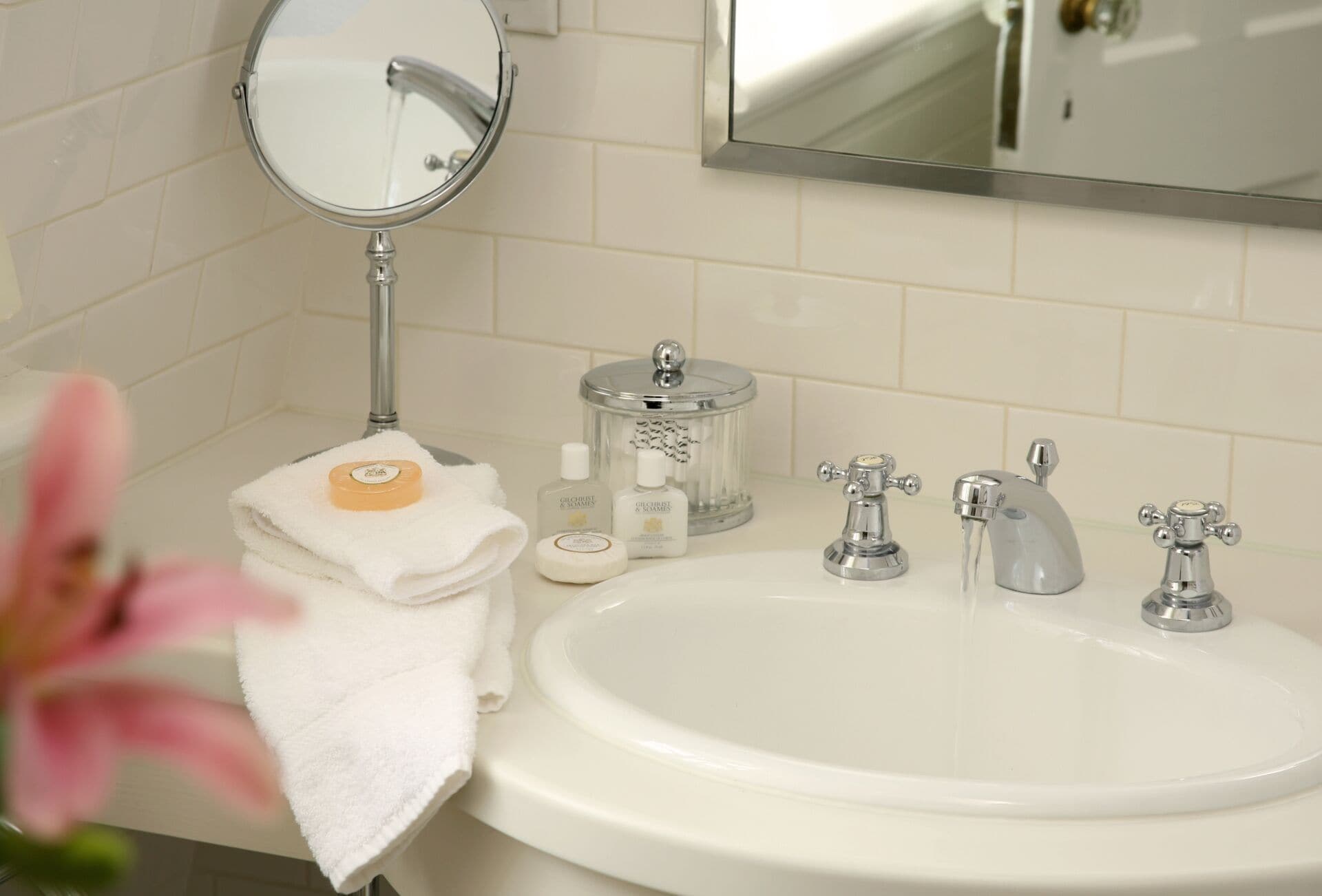 A bathroom with a white sink, two faucets, a mirror, and a towel rack.