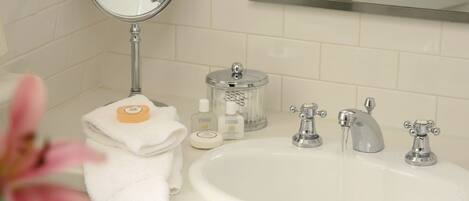 A bathroom with a white sink, two faucets, a mirror, and a towel rack.