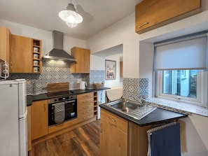 Una cocina compacta con armarios de madera, un horno empotrado y una ventana con vistas.