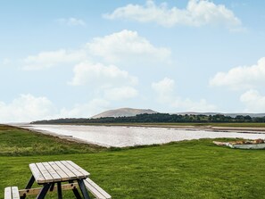 Een picknicktafel in een grasveld met een rivier en heuvels op de achtergrond.