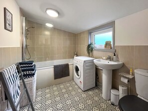 Een kleine badkamer met een wasmachine, wastafel en toilet.