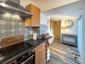 Une cuisine moderne avec un mur arrière décoré de motifs, des armoires en bois, un four encastré et une horloge au mur.