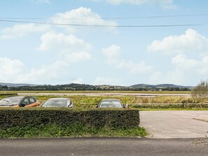 Ein Parkplatz mit drei geparkten Autos in der Nähe eines Hecken.