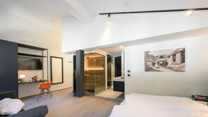 Moderni hotellihuone, jossa on sänky, työpöytä tuolilla, vaatekaappi ja kylpyhuone.