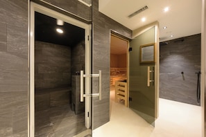 A modern bathroom with a glass shower enclosure, a visible towel rack, and a showerhead. - Boutique Hotel Edelweiss (Sankt Anton am Arlberg)